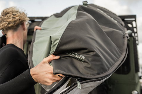 ION Core windsurf board bag being loaded from a vehicle roof rack outdoors