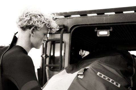 ION Core windsurf board bag being loaded into a 4x4 vehicle, black and white lifestyle shot