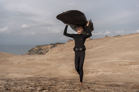 ION Windsurf Boardbag Core Stubby carried overhead on coastal sand dunes