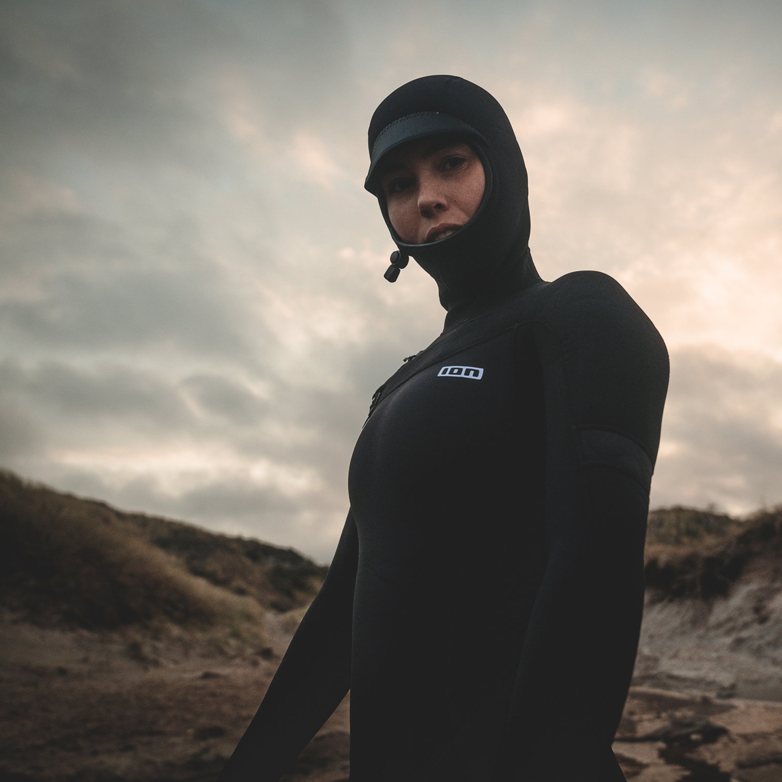 ION Amaze Amp 6/5mm front-zip hooded fullsuit wetsuit for women in black at coastal dunes