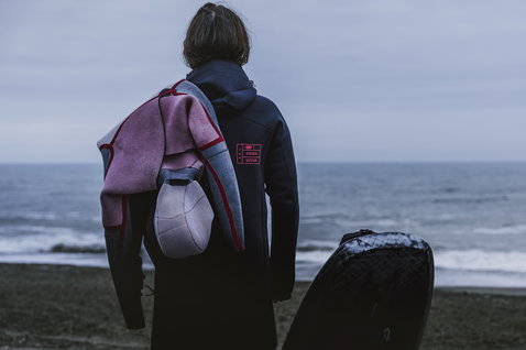 ION Amaze Amp muta integrale 6/5mm zip frontale con cappuccio donna in nero durante il kitesurf in mare