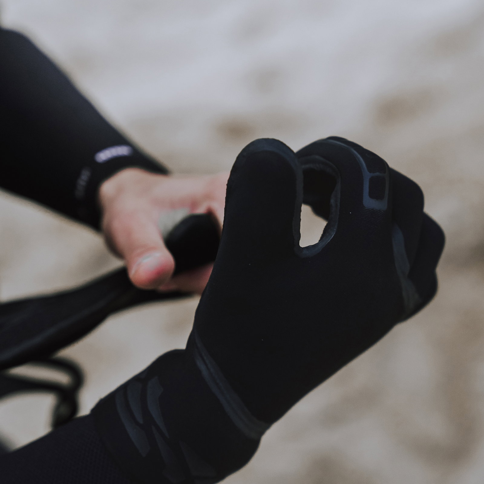 Gants néoprène ION Neo Gloves 4/2mm en noir lors d'une session de kitesurf sur la plage