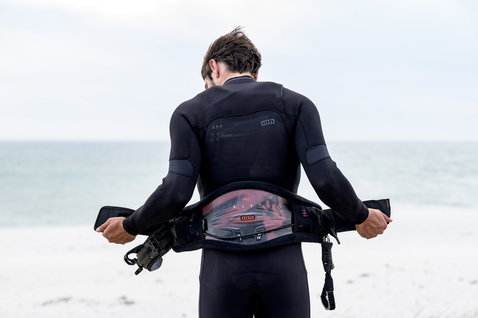ION Riot Curv waist harness during kitesurfing at the beach in black with CURV back plate