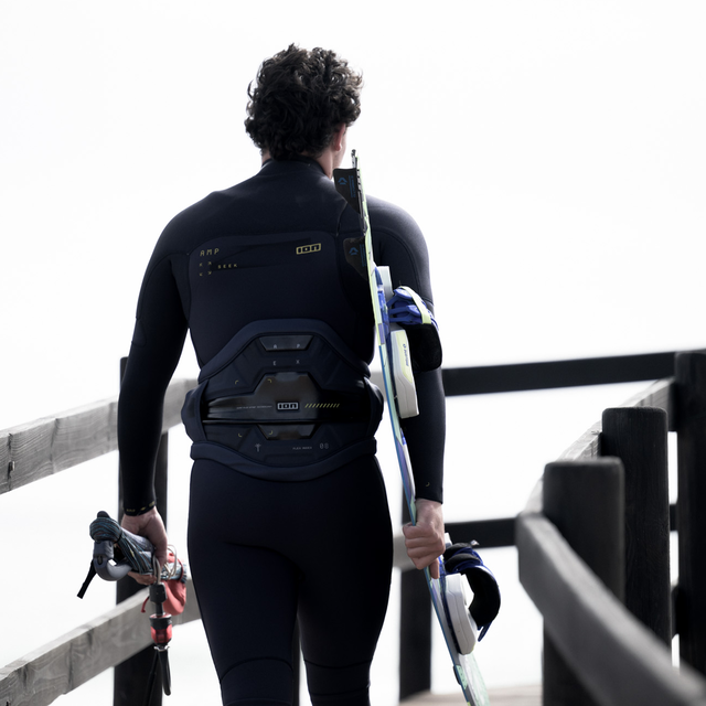 Harnais de taille ION Apex pendant le kitesurf en bord de mer vue arrière en noir avec soutien lombaire Ergo Pad