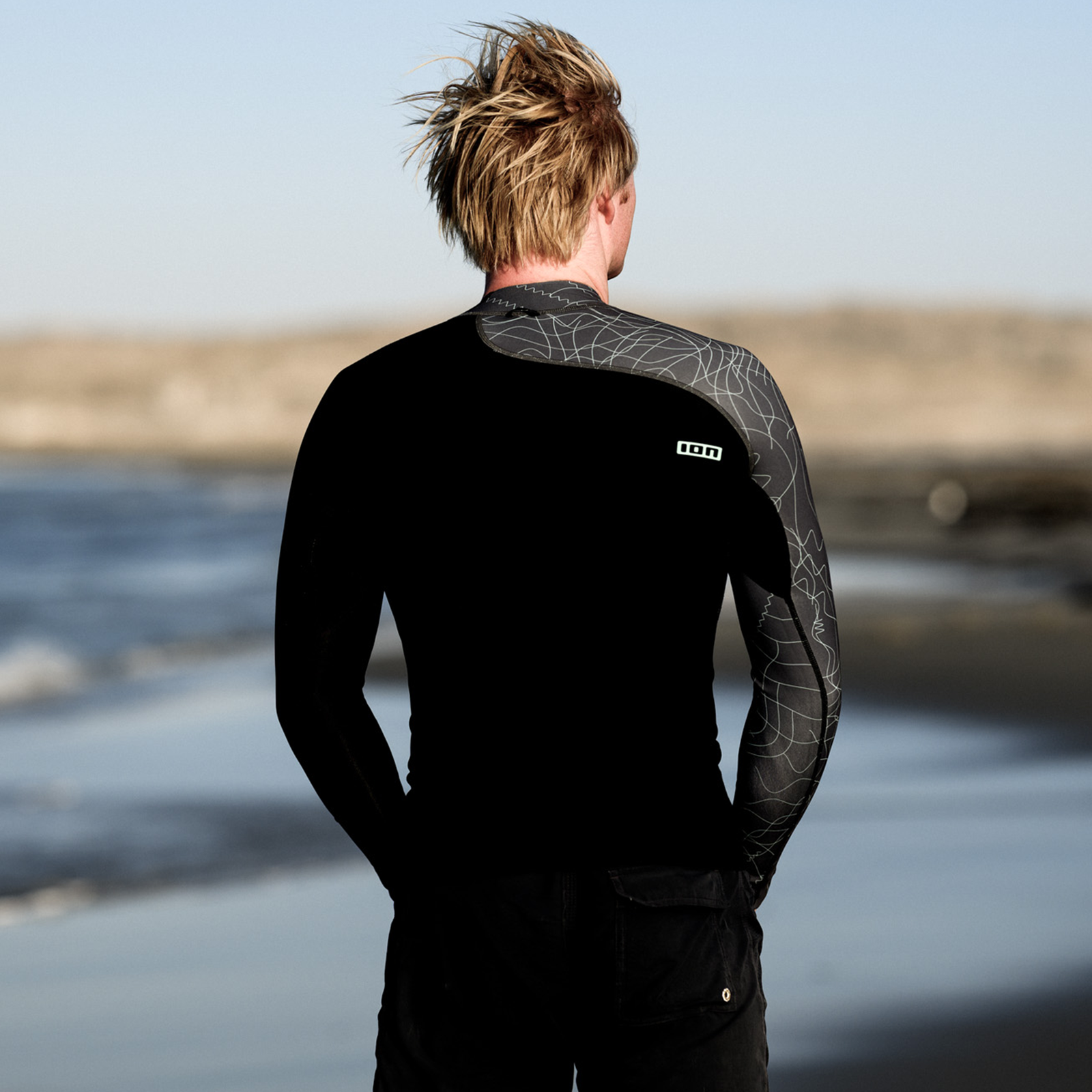 ION Neo Top 0.5 long sleeve neoprene top for men in black and grey during a beach lifestyle shoot