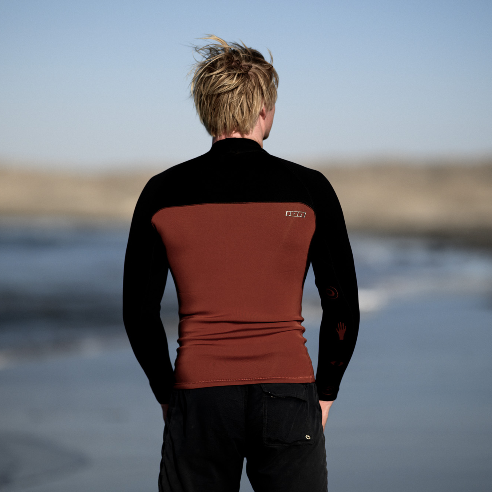 ION Neo Top 2/2 long sleeve neoprene top for men in black and rust brown at the ocean beach