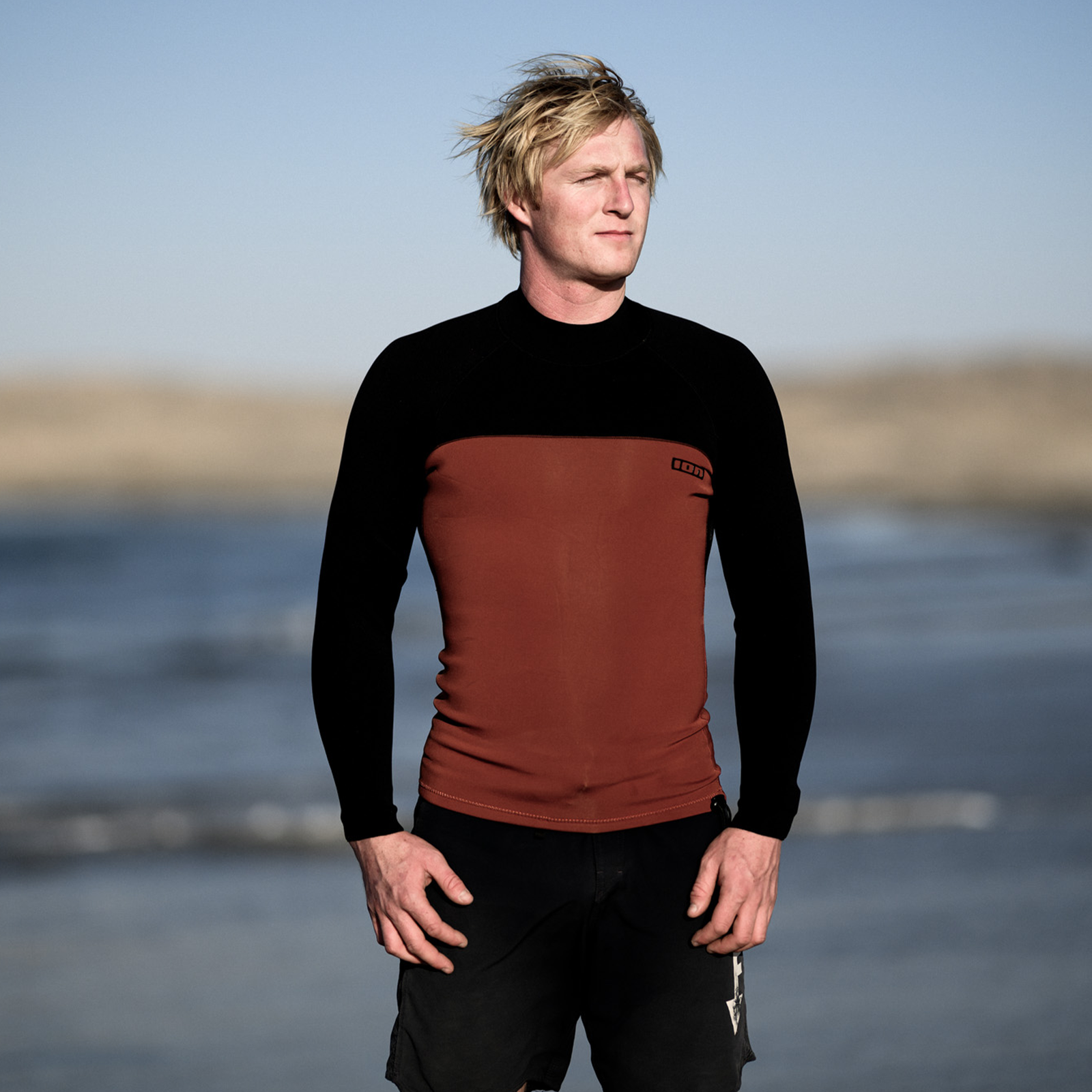 ION Neo Top 2/2 long sleeve neoprene top men in black and rust red, worn at the beach