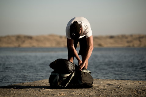 ION Session Duffel Bag 90 l em verde-oliva escuro a ser preparada junto a um lago no deserto
