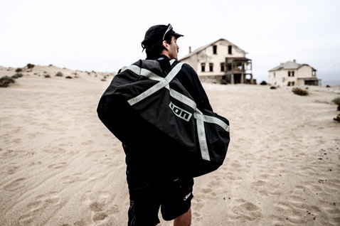 ION Session mala duffel 90l em preto carregada durante viagem em paisagem desértica