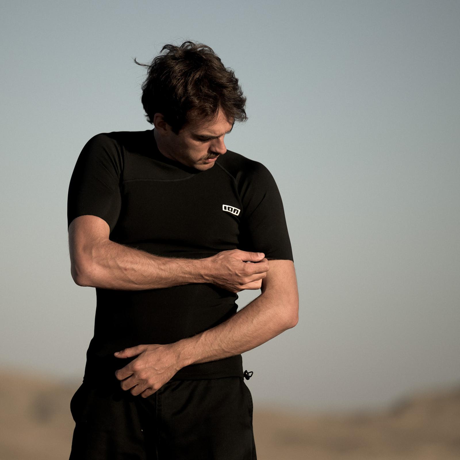 ION Thermo Top short-sleeve men's thermal top in black worn at the coast