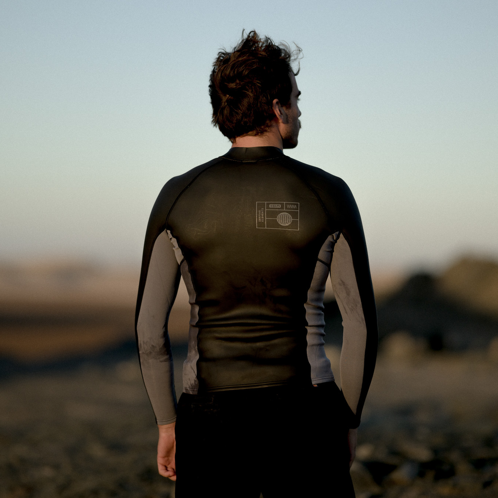 ION Neo Zip Top 2/1 LS Skin men neoprene top in black and taupe during kitesurfing at the coast