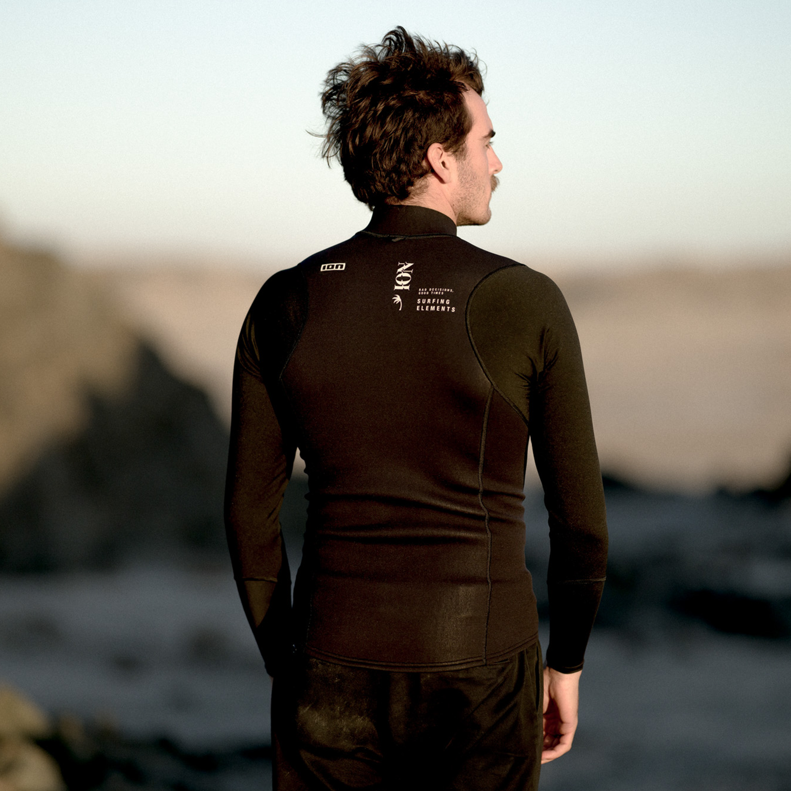 ION Neo Zip Top 2/1mm neoprene long-sleeve top in black during kitesurfing at the coast