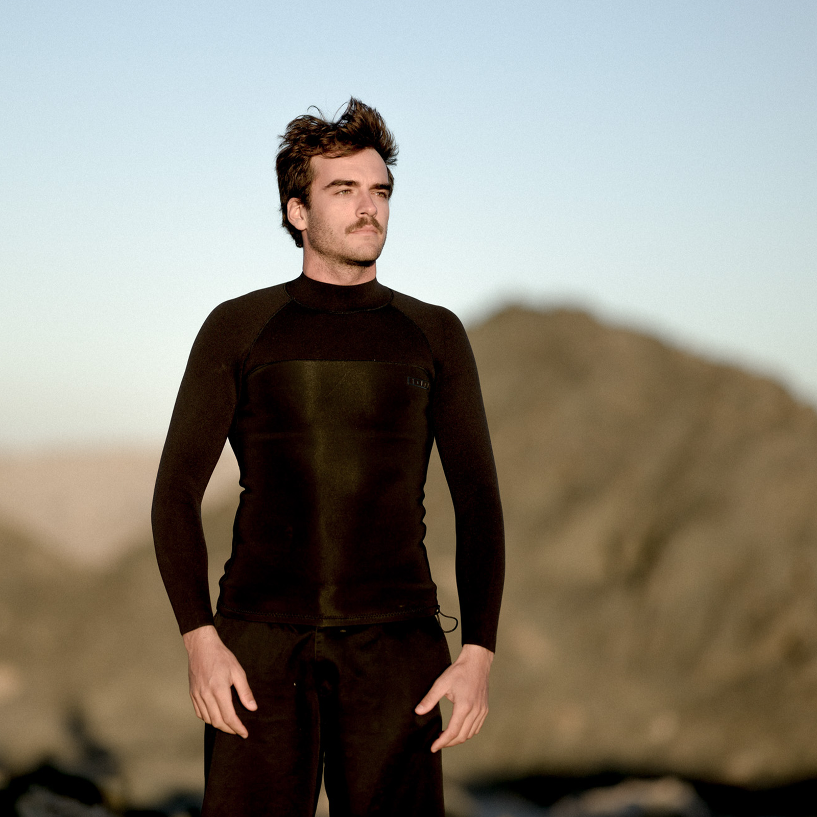 ION Neo Top 2/2 long sleeve neoprene top for men in black worn at the coast