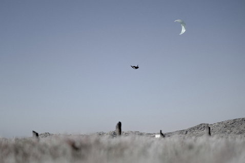 ION Riot Curv waist harness during kitesurfing with big-air jump above beach dunes