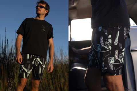 Short de surf ION Ionic 19" homme imprimé intégral noir et vert sauge en contexte lifestyle extérieur