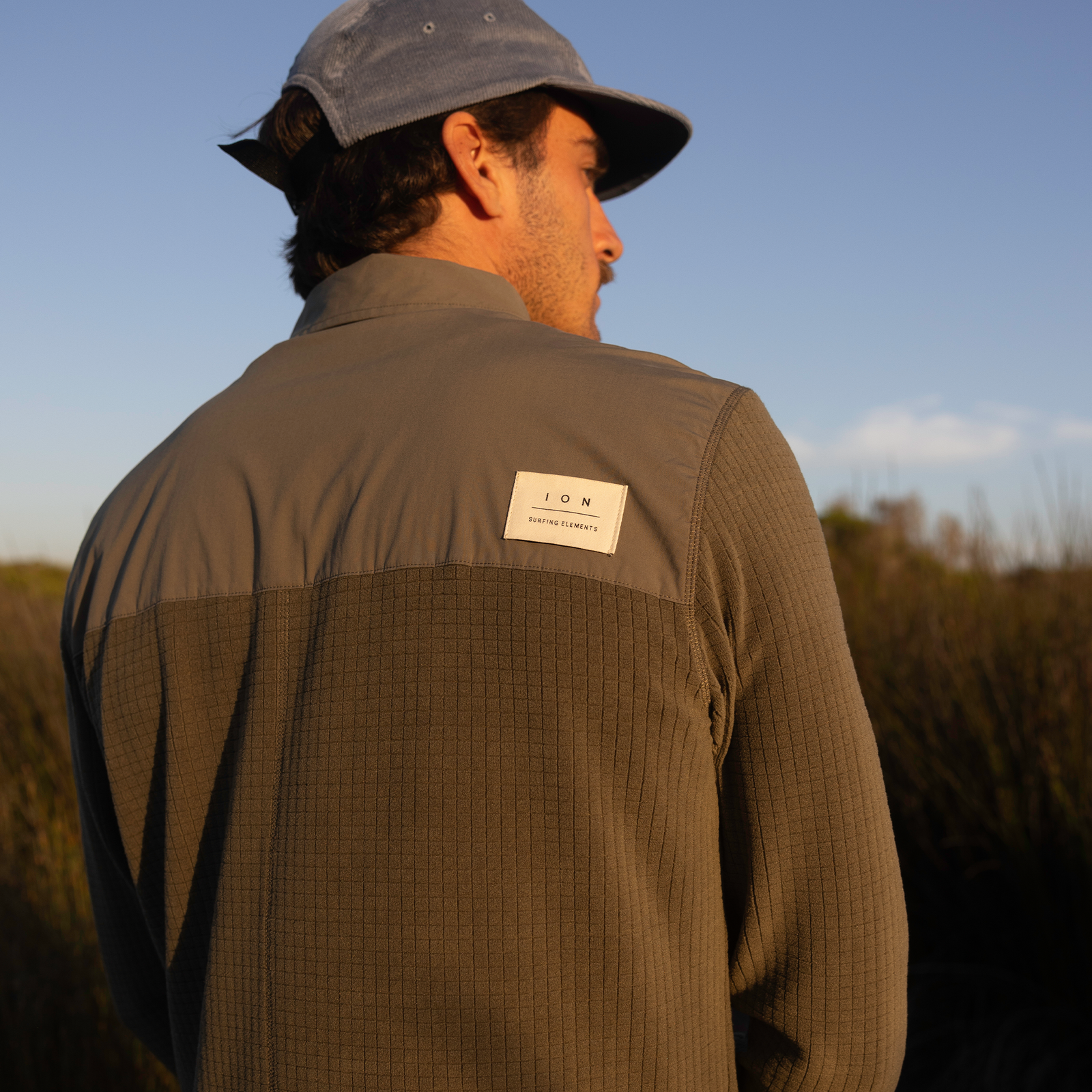 Giacca ION Ionic Fleece unisex in verde oliva con rinforzo spalla indossata all'aperto