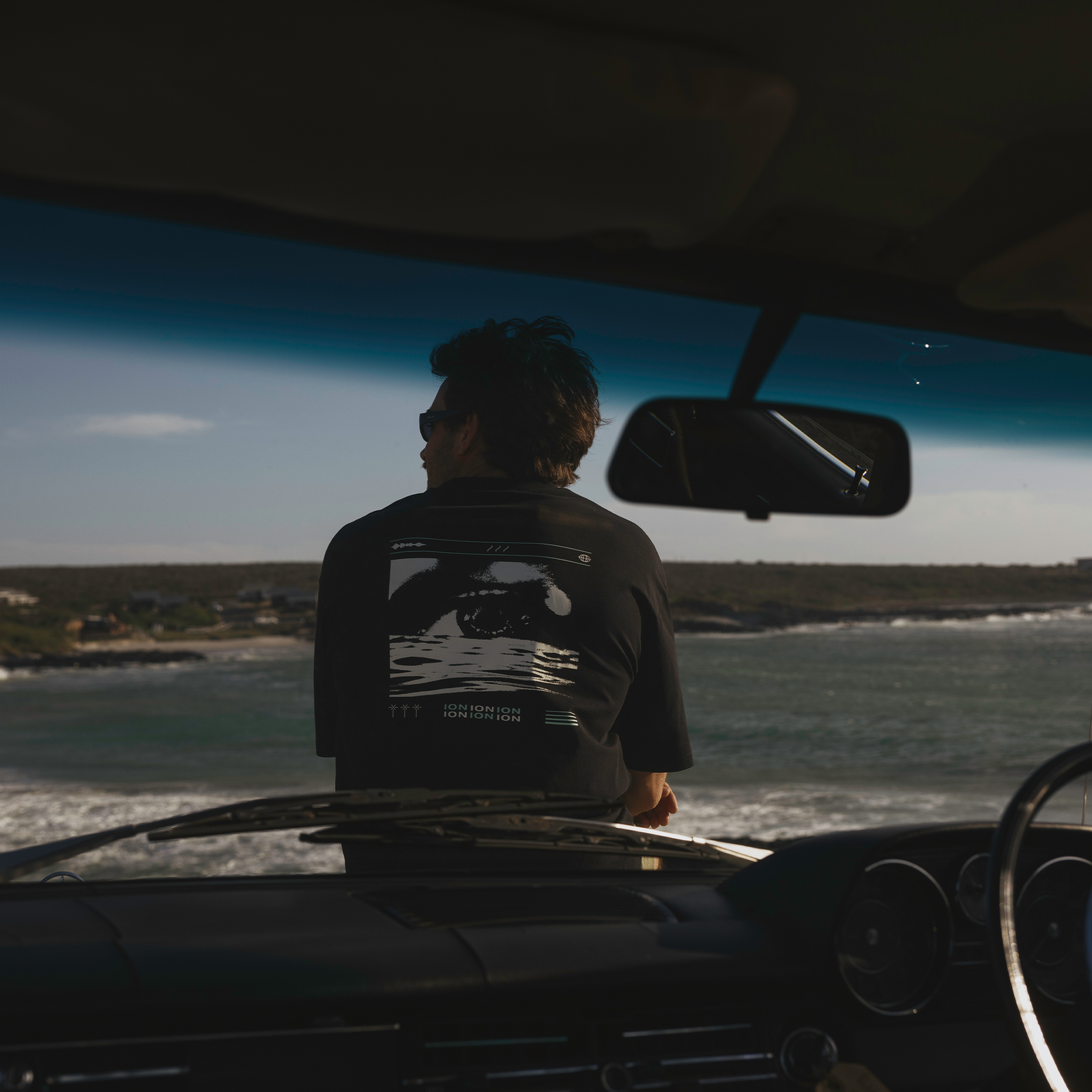 T-shirt ION Vibes SS homme en noir porté en bord de mer — vue de dos avec imprimé graphique