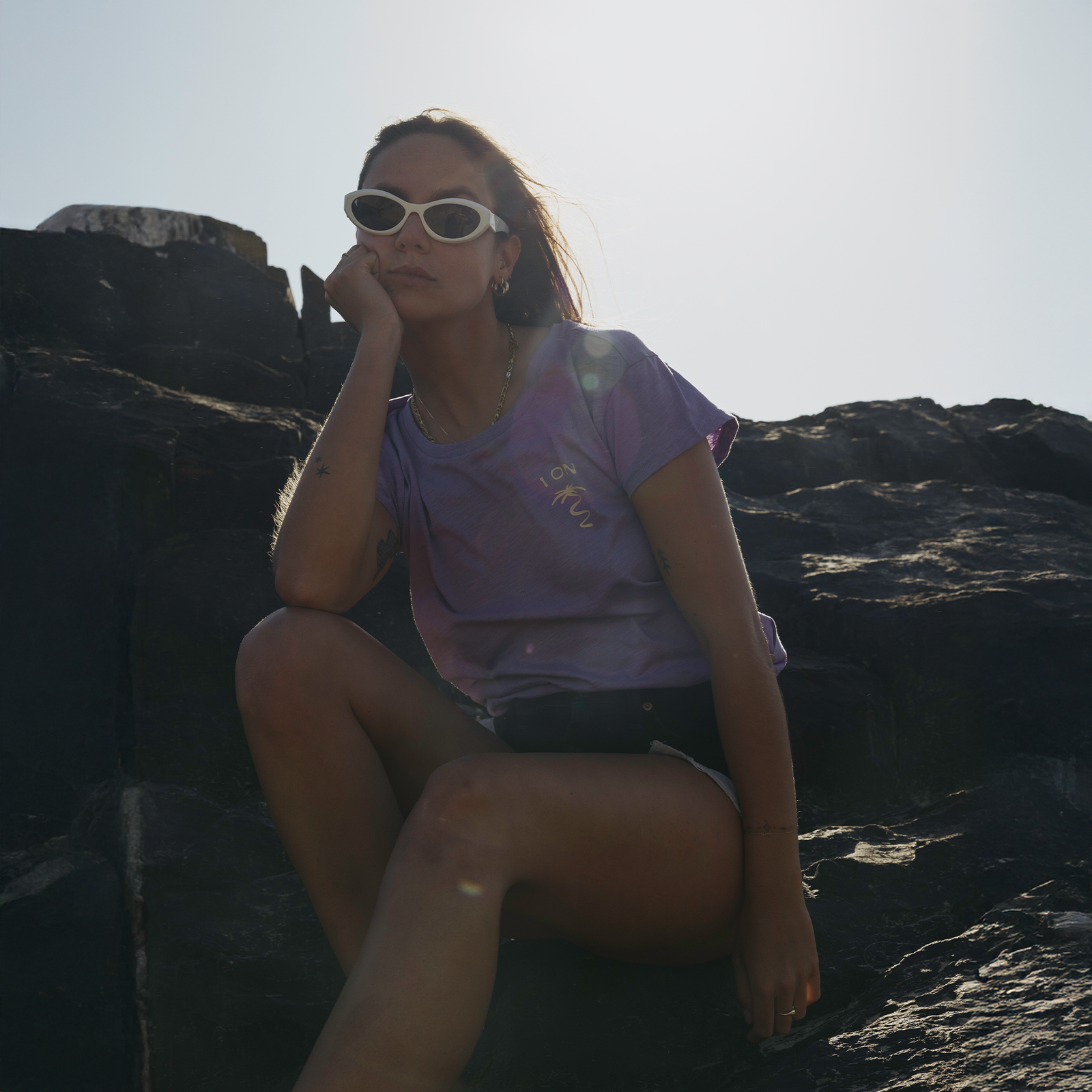 ION Stoked women's short-sleeve tee in lavender at rocky coastal cliffs