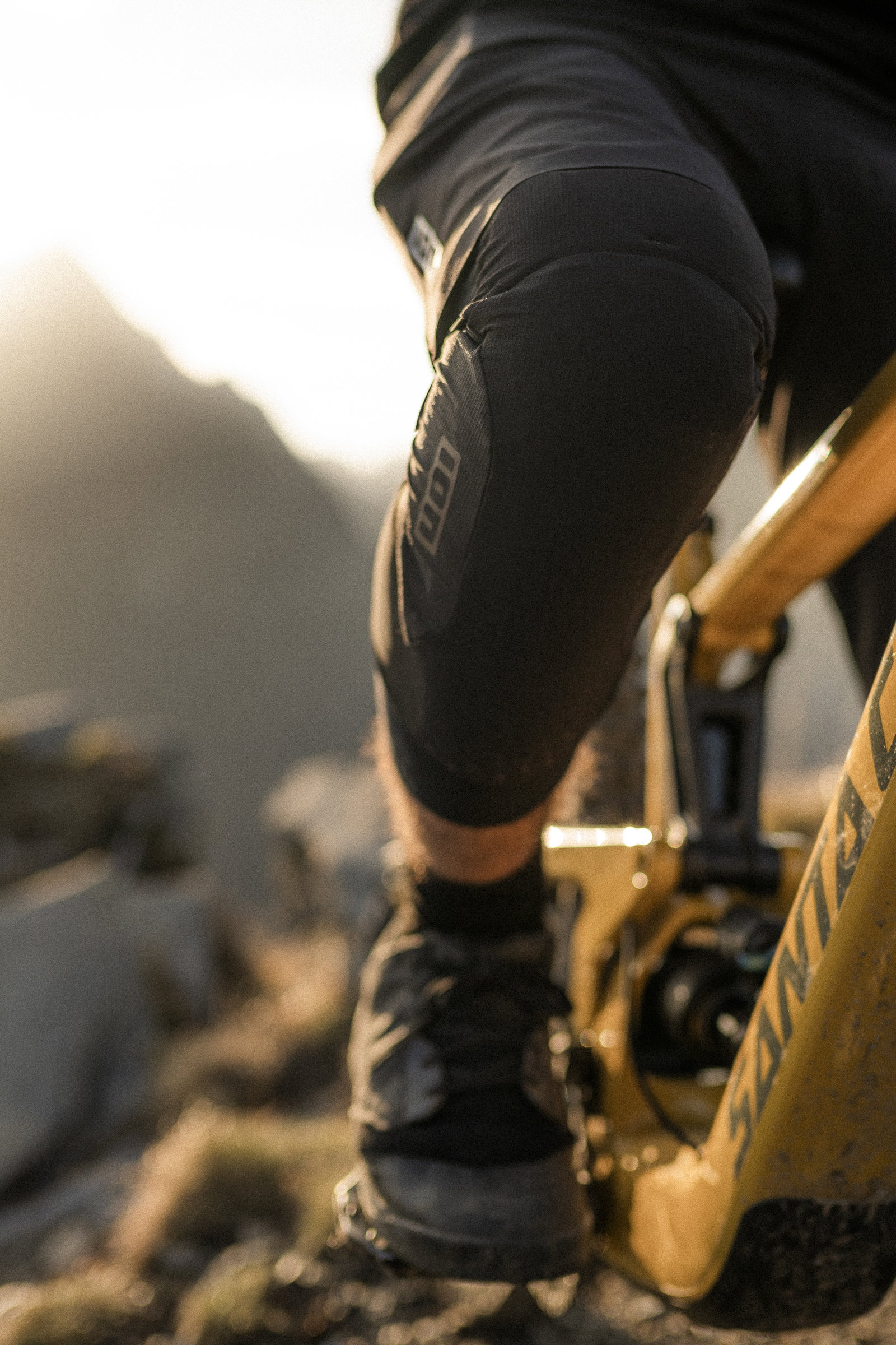 ION Bike ARCON LT knee guard CE L2 during mountain biking on rocky trail in black