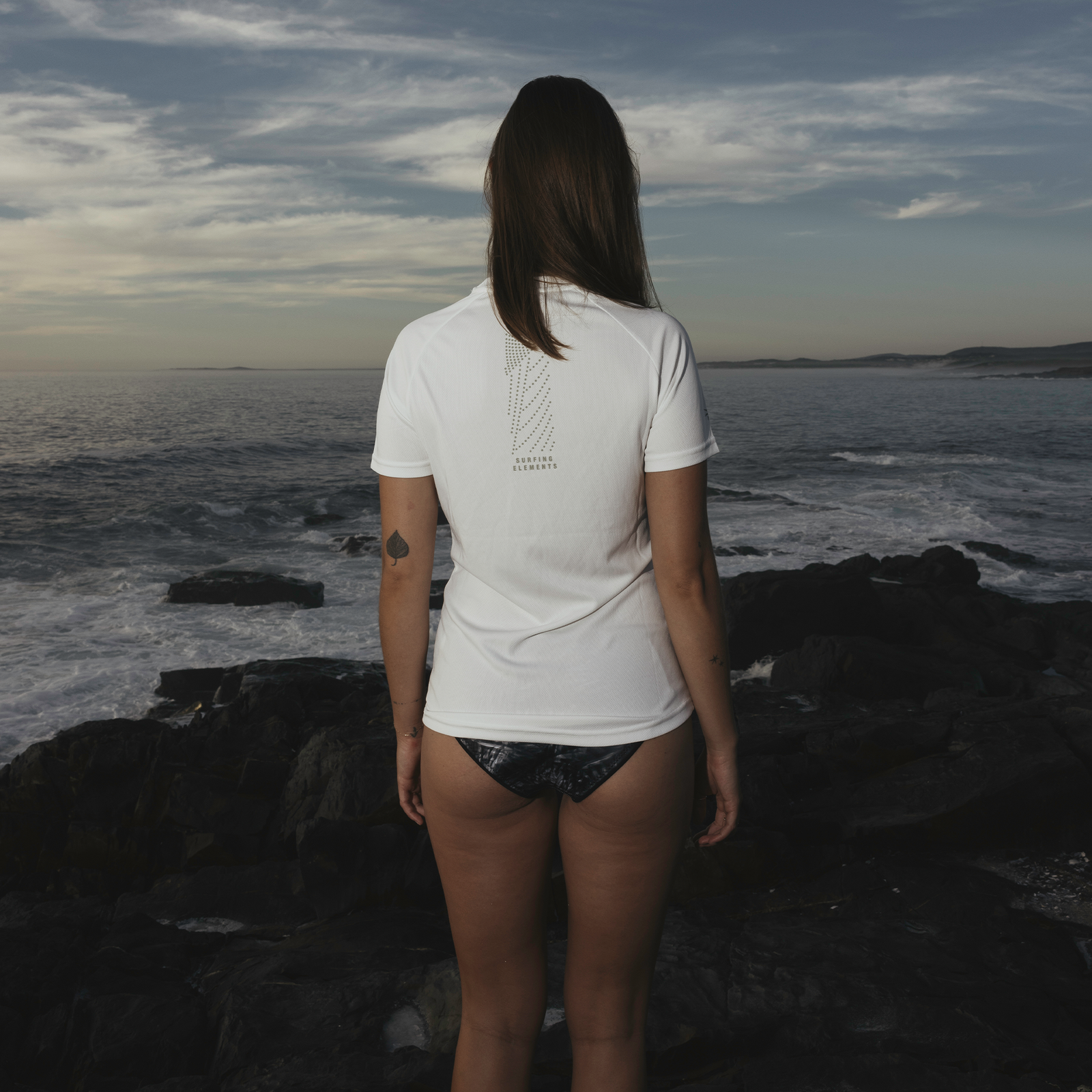 ION Wetshirt short sleeve women in white during kitesurfing at the rocky coast