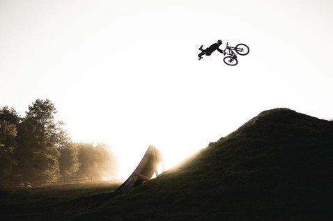 ION Scrub Amp BAT Fahrradhose beim Freeriden an einem Dirt-Jump-Kurs im Gegenlicht