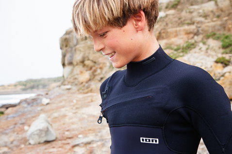 ION Capture Amp 4/3mm front-zip junior fullsuit in dark navy at rocky coast