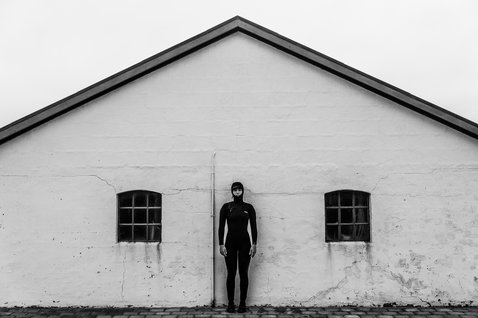 ION Neo Hoody Lite women neoprene hoody in black worn on model against whitewashed building wall