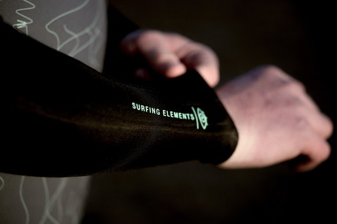 ION Seek Core 3/2mm Front-Zip Shorty Neoprenanzug in schwarz, Ärmeldetail mit Surfing Elements Print