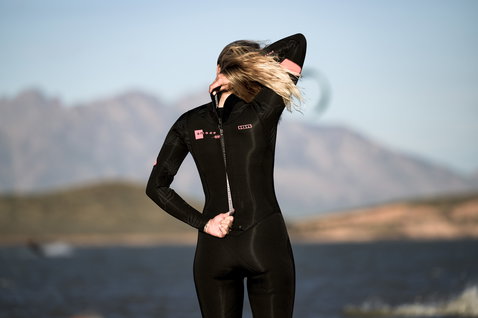 ION Amaze Core 4/3mm Backzip Fullsuit in schwarz mit rosa Details, Rückenansicht an der Küste