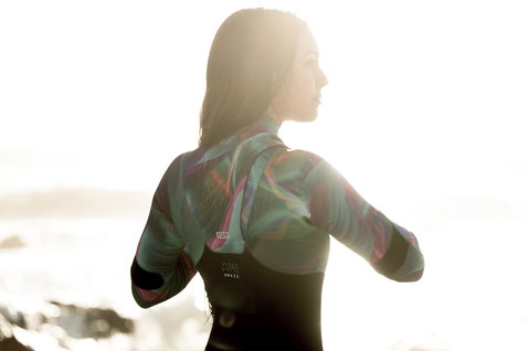 ION Amaze Core 3/2mm front-zip fullsuit wetsuit during watersports at the coast in backlit golden light
