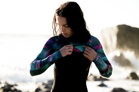 ION Amaze Core 5/4mm Frontzip Neoprenanzug in schwarz, petrol und lila beim Surfen an der Küste