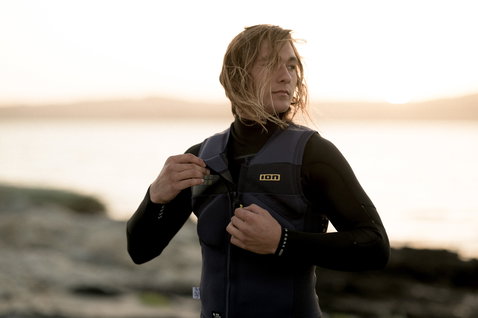 ION Vector Vest Amp Front Zip impact vest during kitesurfing on a rocky coastline at golden hour