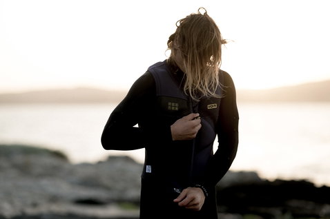 ION Vector Vest Amp front zip impact vest in black worn during kitesurfing at a rocky coastal shoreline