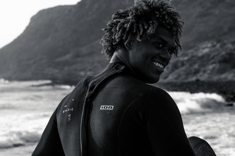 Combinaison shorty ION Static 2/2mm zip dos en noir lors de session surf sur côte rocheuse