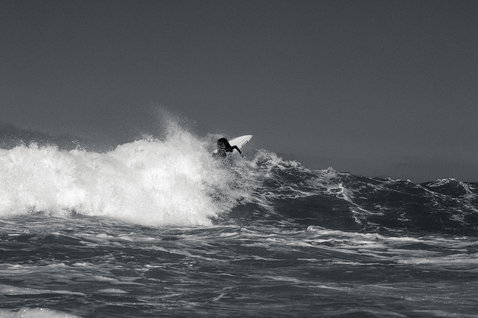 ION Capture muta integrale 6/5mm con cappuccio zip frontale durante il surf su onda in oceano
