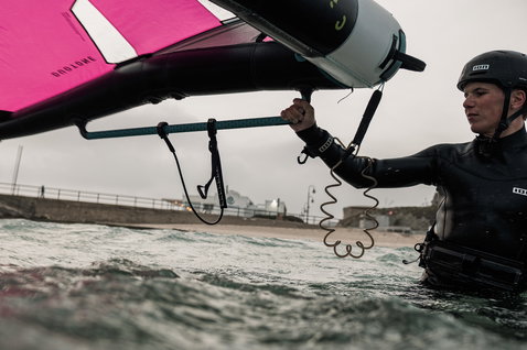 ION Wing Leash Core Coiled Wrist durante il wing foiling sull'oceano in nero