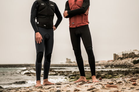 ION Collision Vest Core Front Zip men's impact vest in terracotta and black worn on rocky beach coastline