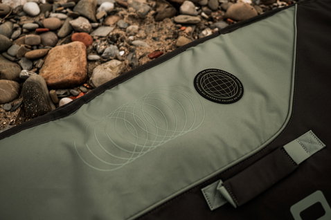 ION Core Slim wing boardbag in olive green, detail view of logo badge on pebble beach