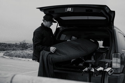 ION Wing Sock 5'5" board cover during transport at the car in dark grey