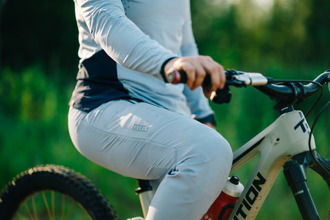 ION Scrub Amp BAT women long-sleeve cycling jersey in light grey during mountain biking in forest
