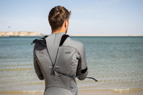 ION Seek Core muta integrale 5/4mm zip dorsale in grigio durante il kitesurf in spiaggia