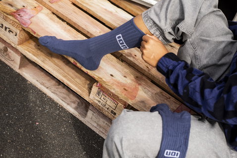 Chaussettes longues unisexes ION Ionic en bleu ardoise portées sur un pied posé sur une palette en bois