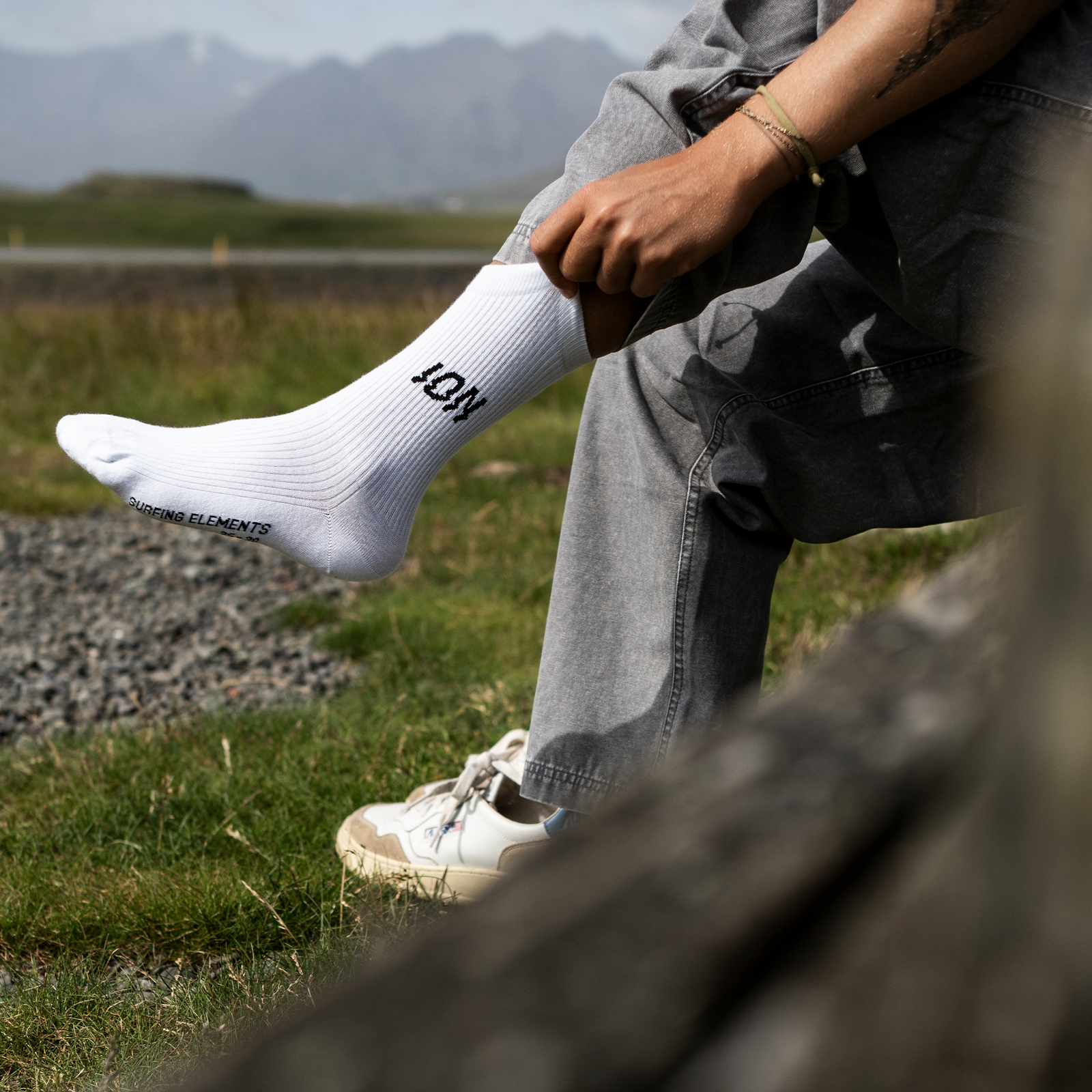 ION Ionic Light cotton crew socks in white worn outdoors on rocky coastal terrain