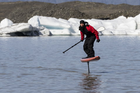 ION Fuse Lightweight back-zip drysuit during foiling at a glacial lagoon in Iceland in black and red