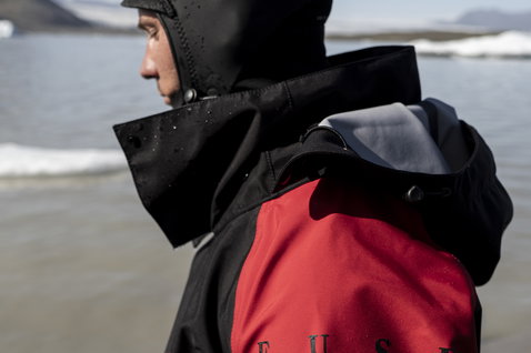 ION Fuse Lightweight Drysuit back-zip during kitesurfing on an arctic beach in Iceland in black and red