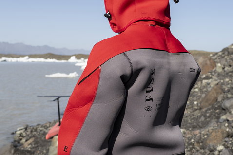 ION Fuse Drysuit 4/3mm back-zip fullsuit in red and grey during kitesurfing at the Icelandic coast