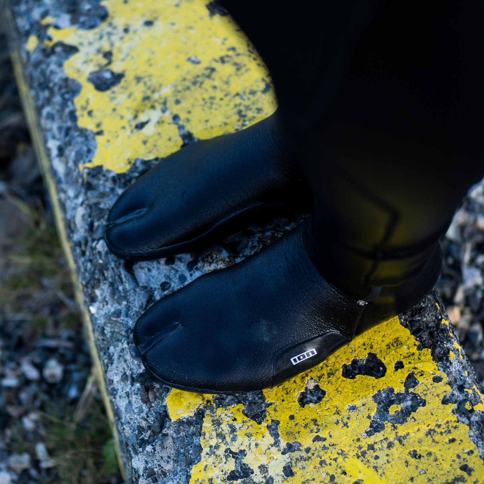 ION Ballistic split-toe neoprene socks 3/2mm in black worn during watersports on rocky terrain