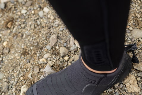 ION Plasma Shoes 2.5 Round Toe neoprene water shoes in black during kitesurfing on a rocky beach