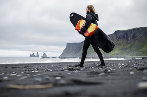 Calzino tavola ION Surf Sock Stubby in nero su spiaggia di sabbia nera vulcanica in Islanda