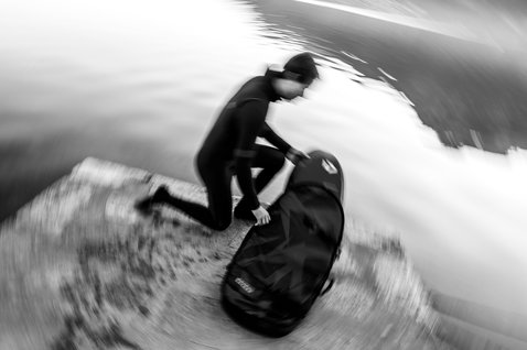 ION Pump Foil Boardbag Tec 3'4'' in black during foiling at a rocky shoreline